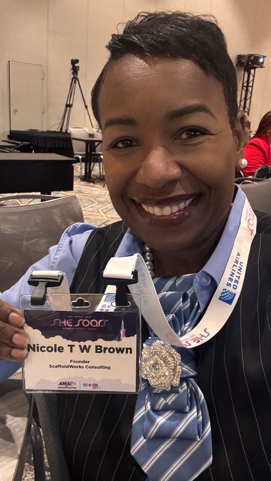 Smiling at the She Soars event with a conference badge