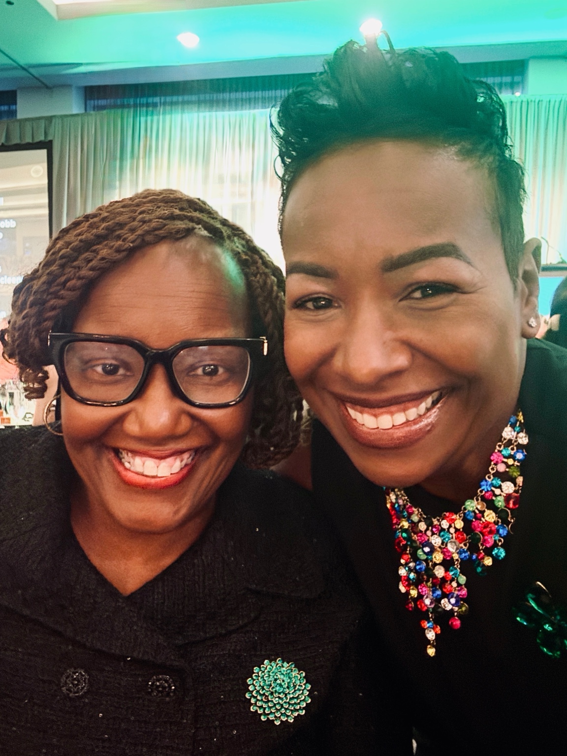 Two people sharing a smiling selfie at an indoor gathering
