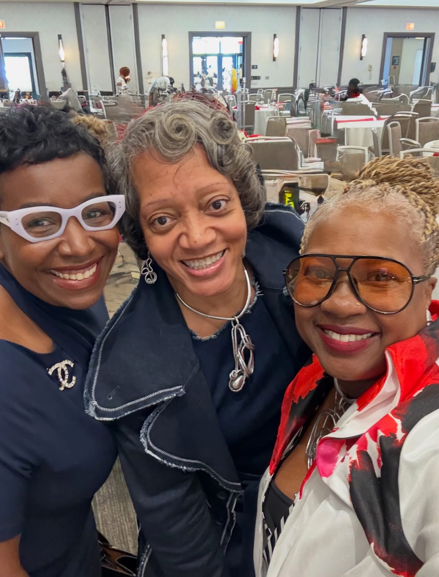 Three people sharing a smiling selfie in an event hall