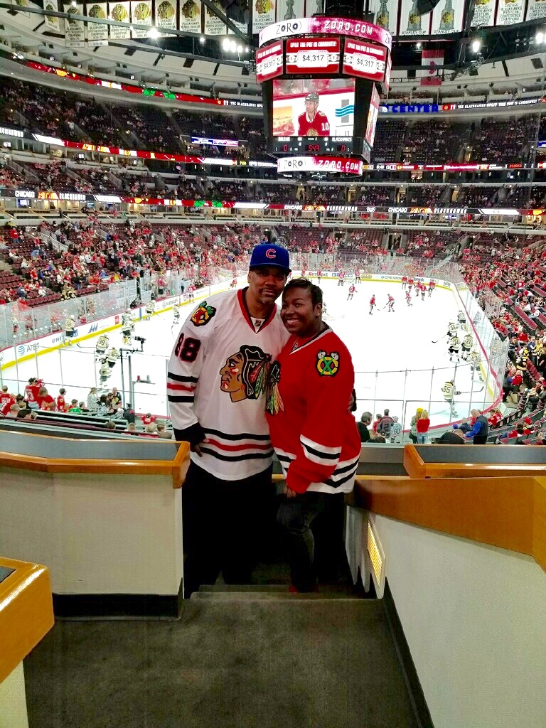 Two people wearing Chicago Blackhawks jerseys at a hockey game