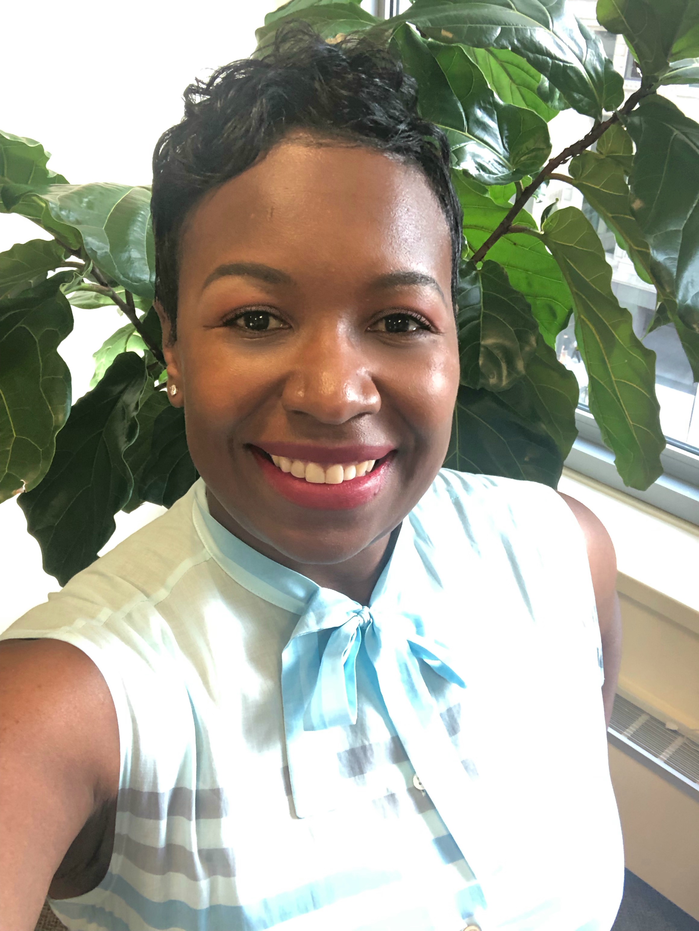 Smiling portrait beside a leafy indoor plant