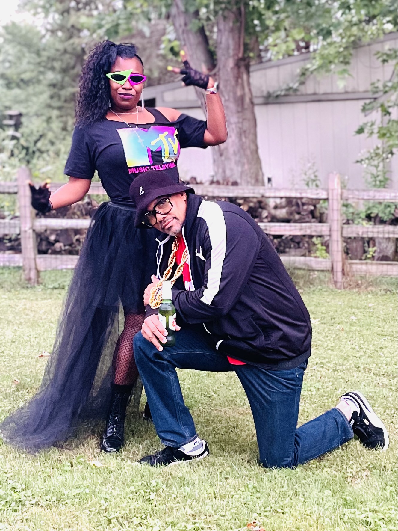 Two people posing outdoors in colorful retro music-inspired outfits
