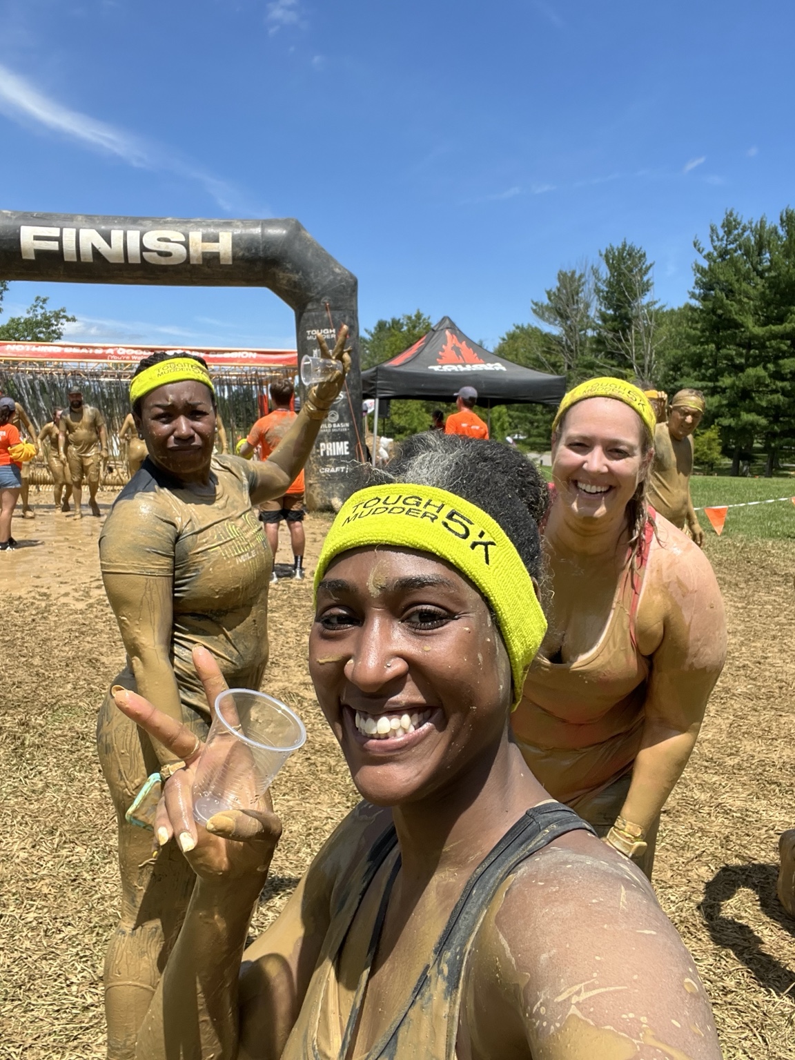 Three muddy participants celebrating at the Tough Mudder 5K finish line