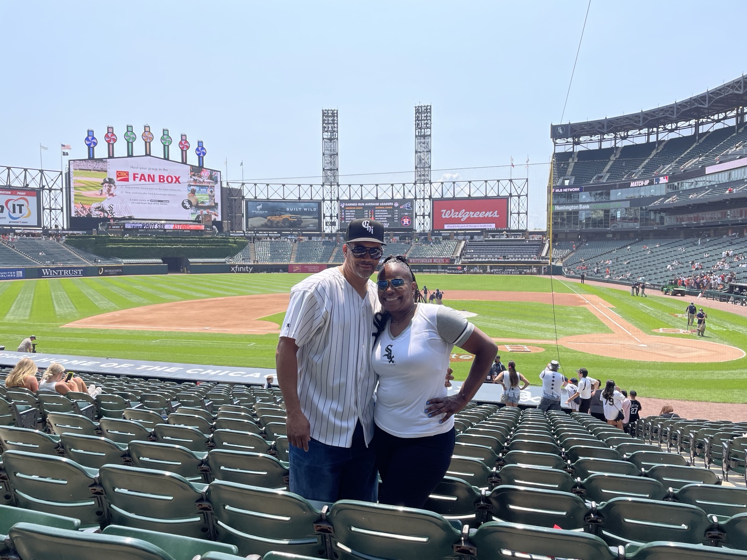 Two baseball fans posing with the Chicago White Sox field behind them