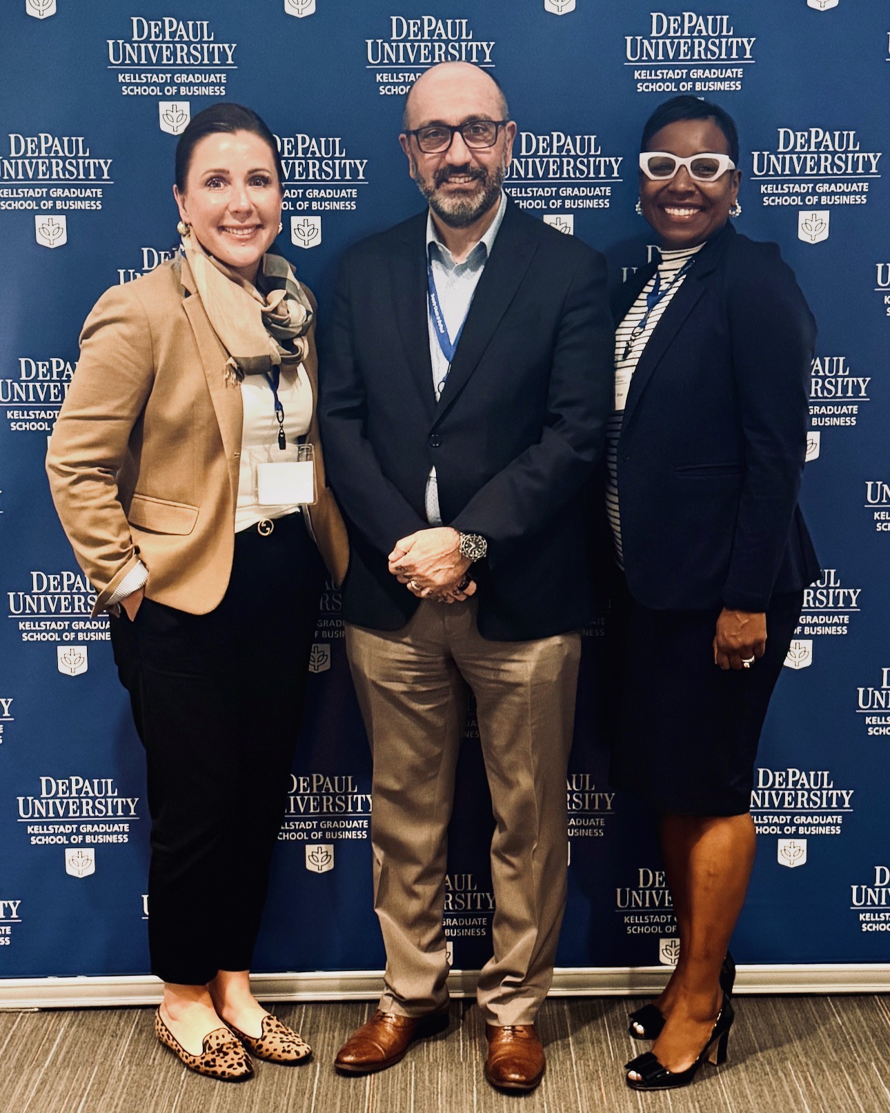 Three people posing in front of a DePaul University Kellstadt Graduate School of Business backdrop