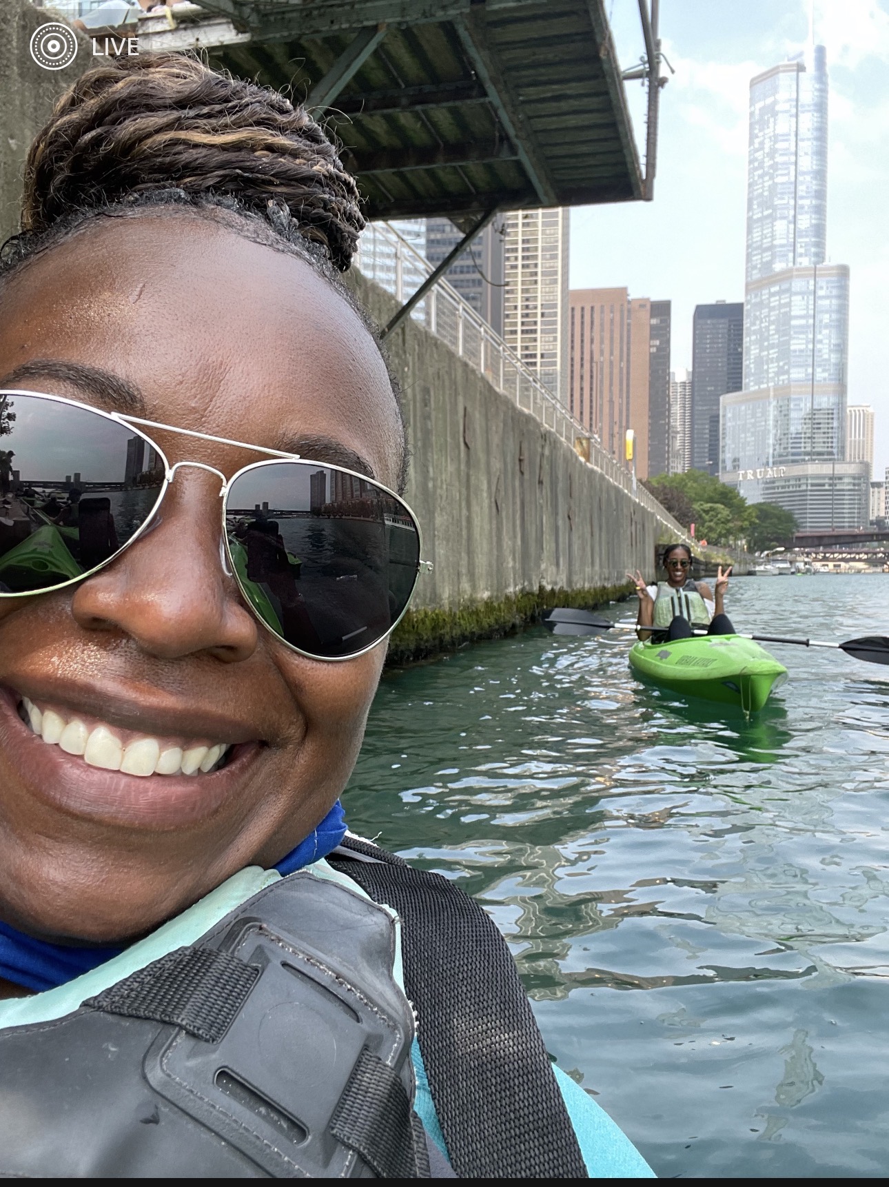 Two kayakers on the Chicago River with downtown buildings behind them