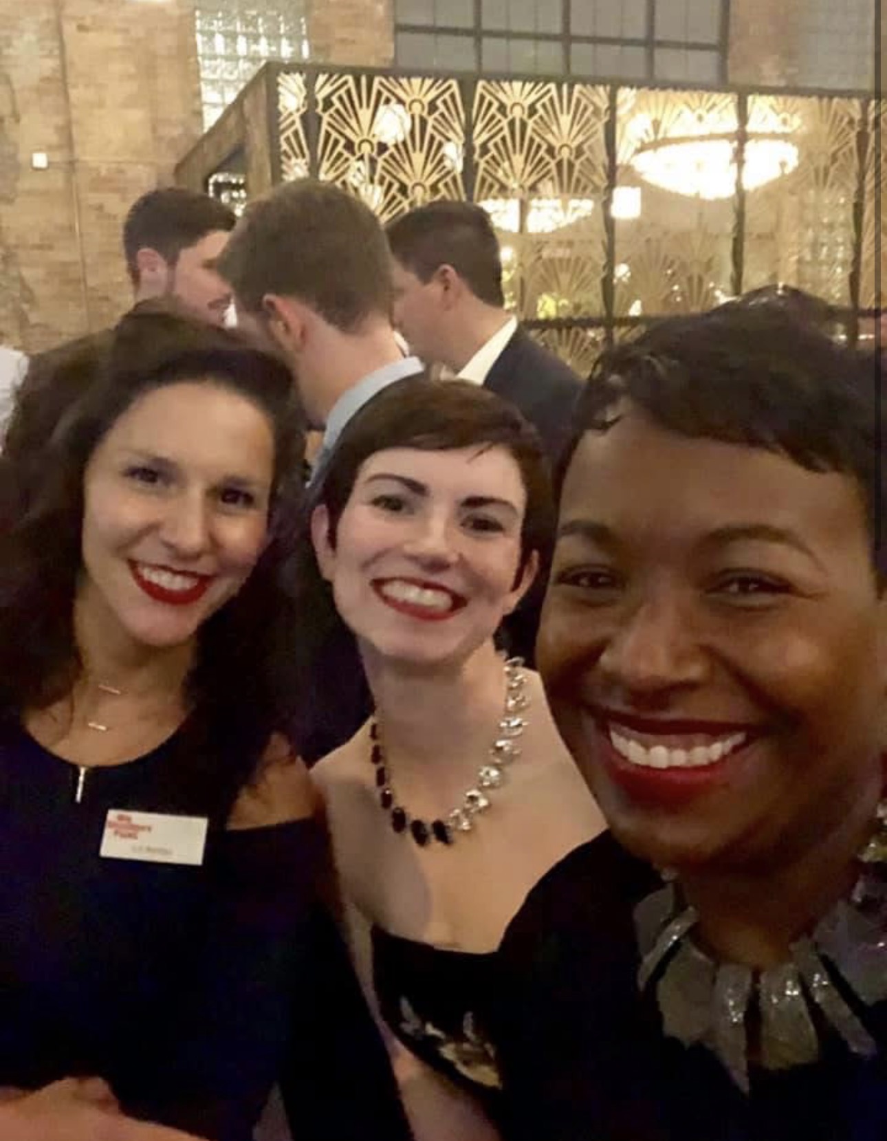 Three women smiling for a selfie at an indoor reception