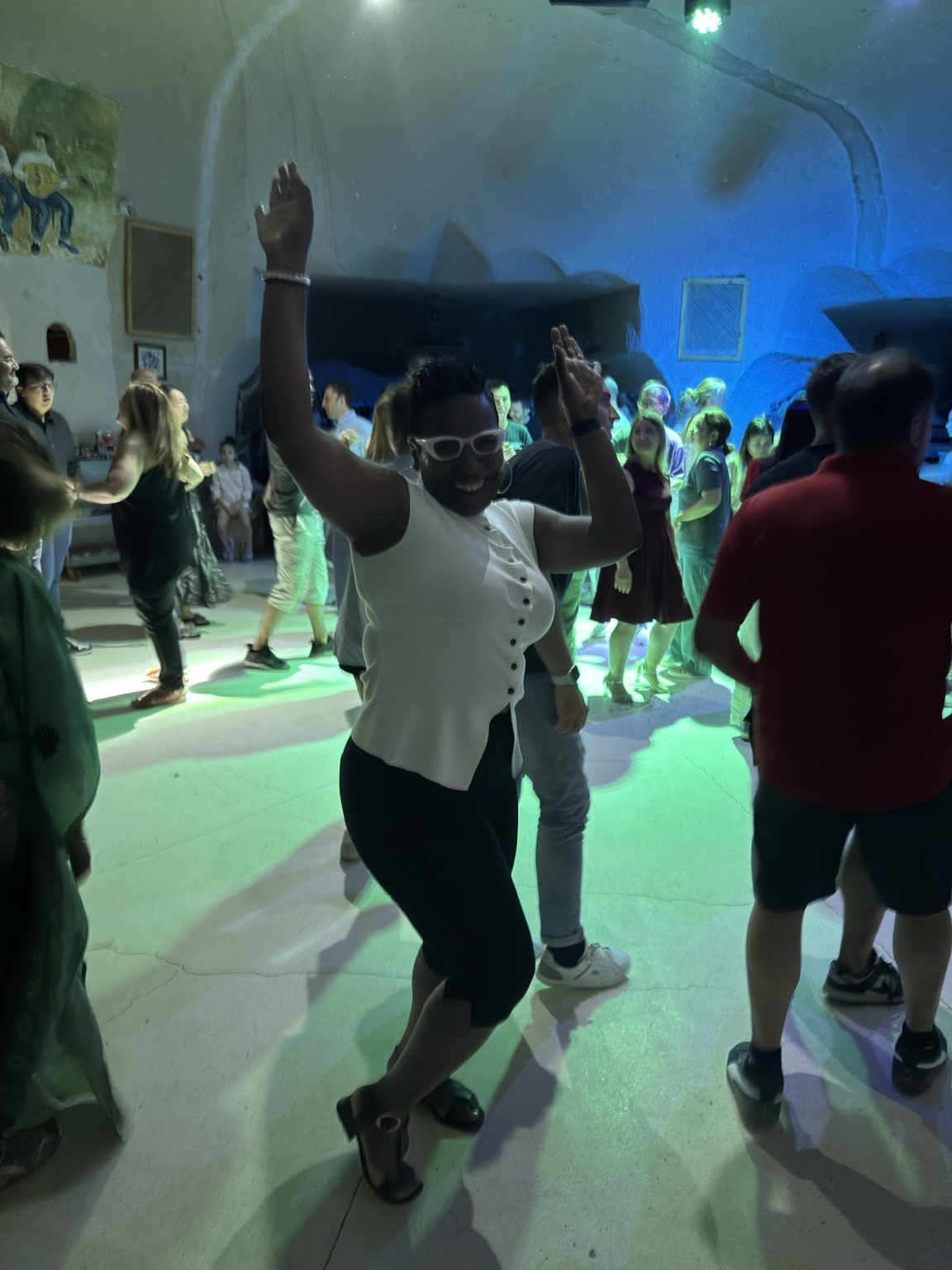 Dancing with raised arms on a dance floor lit in blue and green