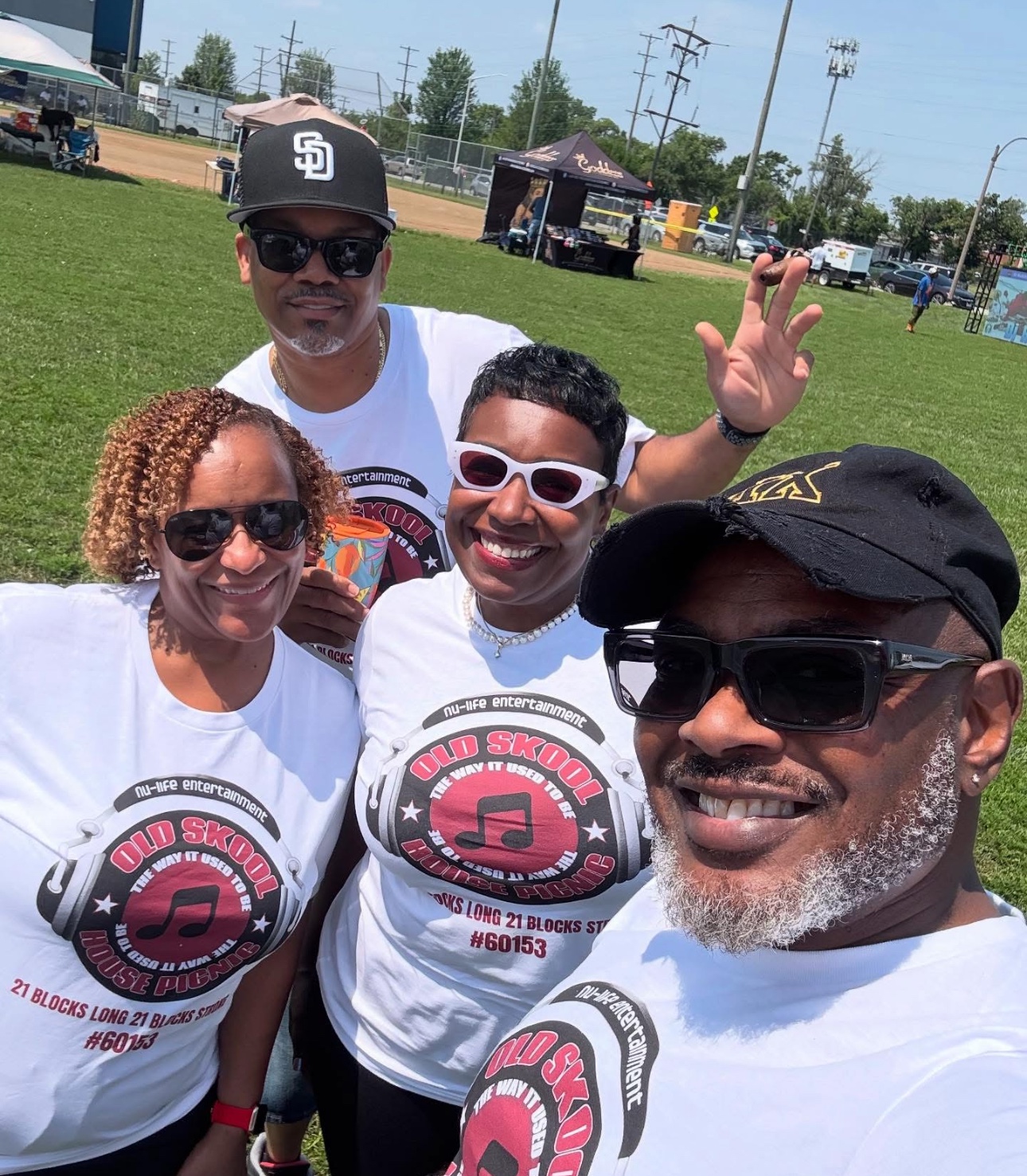 Four people smiling outdoors in matching Old Skool House Picnic shirts