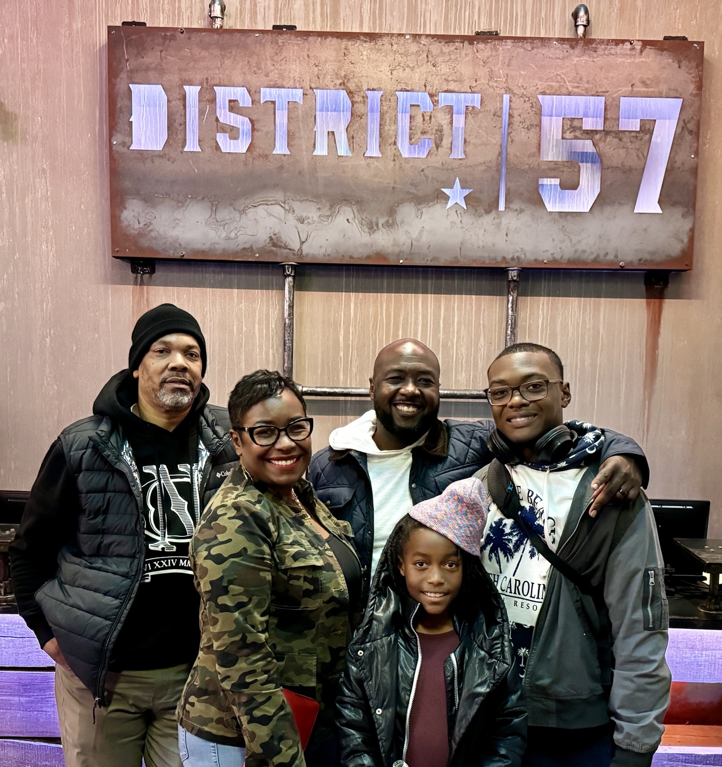 A group of adults and children posing beneath a District 57 sign